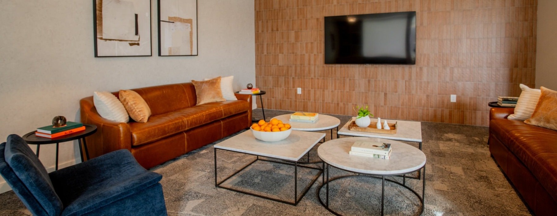 a lounge area with a tv, chair, couches and tables